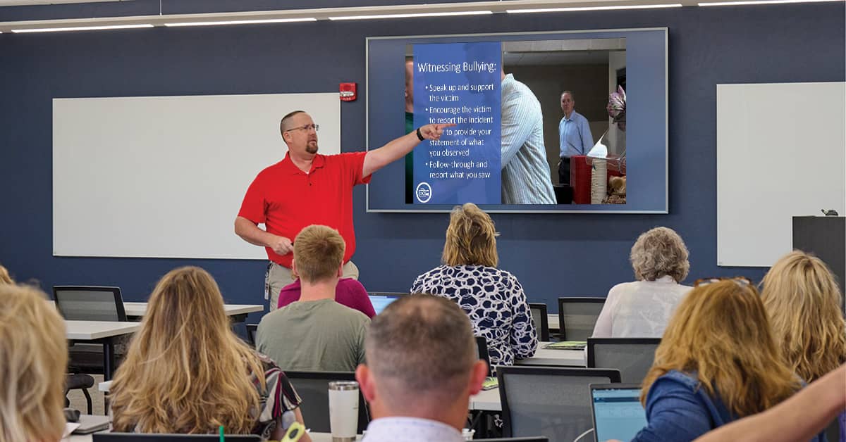 Trainer presenting a workplace bullying awareness slide to a group of professionals during a corporate training session.