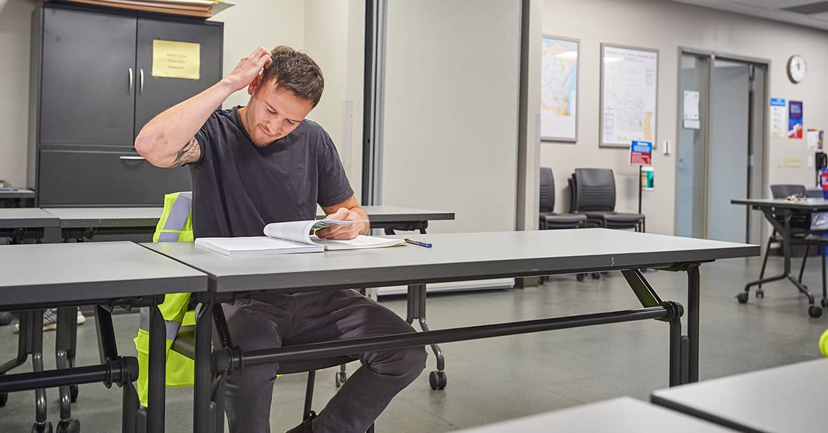 Employee sitting in a training classroom reviewing materials, illustrating challenges with retaining training information
