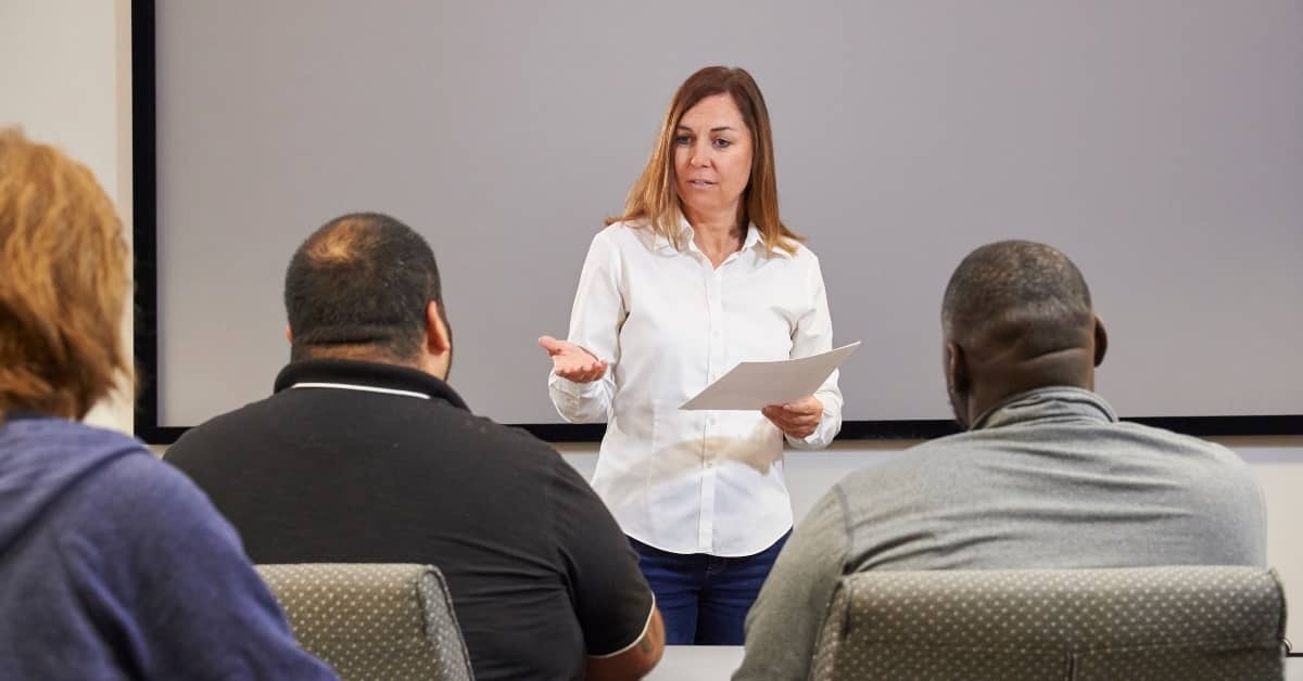 Instructor leading an in‑person safety training session with employees in a classroom setting