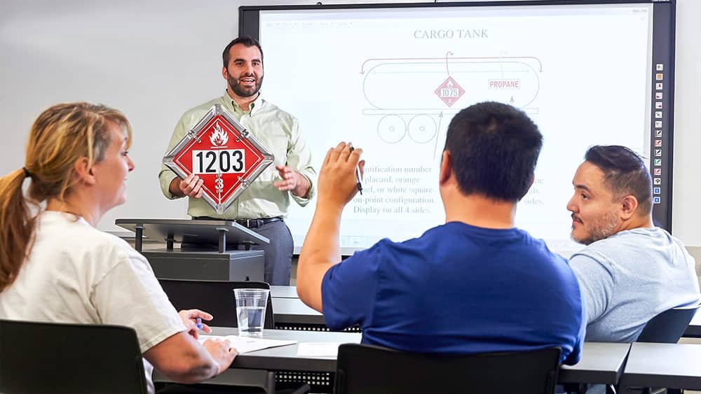Instructor holding a hazmat placard in a classroom setting